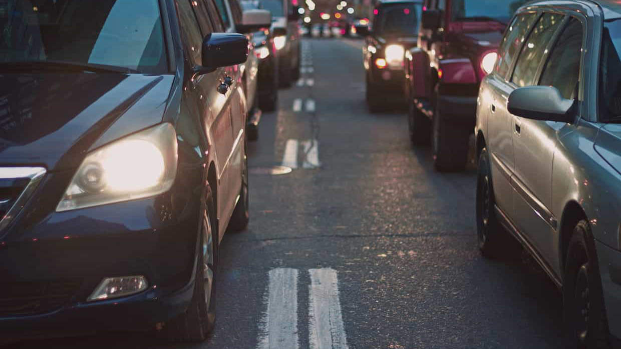 Via urbana con coches estacionados y parados